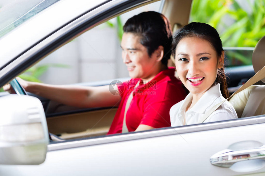 亚洲夫妇在回家的车道上驾驶新车图片