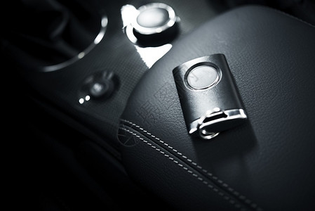 放置在汽车扶手上的汽车钥匙和遥控器与黑色皮革的豪华跑车内部机动化主题图片