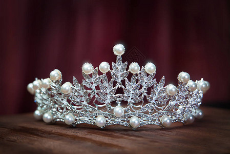 优雅的钻石王冠木质表面饰有珍珠背景图片