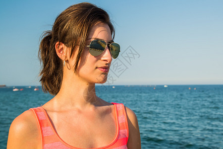 美丽的女孩带着太阳眼镜以海图片