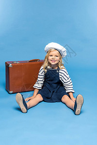 可爱的小女孩坐在手提箱旁边笑着微笑图片