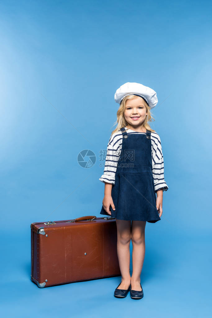 整个画面的美丽小女孩站在手提箱和笑着微笑的镜头中图片