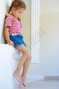 穿着短裤的漂亮小女孩坐在石图片