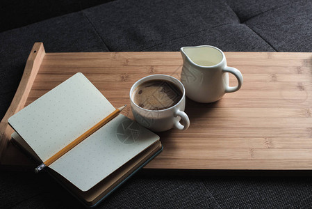 咖啡牛奶和笔记本用铅笔放在沙图片