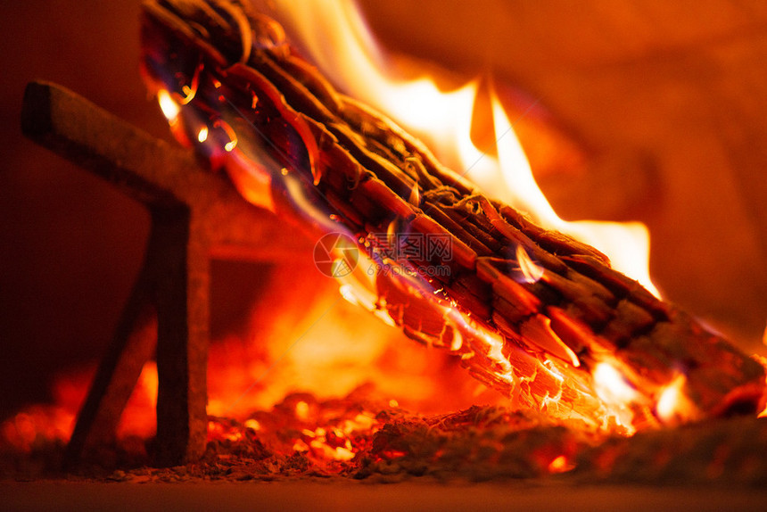 带有燃烧原木的传统燃木砖炉内部图片