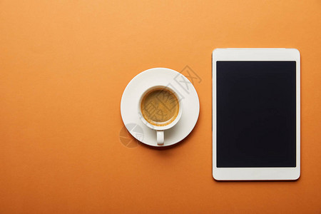 橙色咖啡杯旁有空白屏幕的数字图片