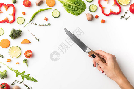 以白色隔离的蔬菜在桌子上用刀子割图片