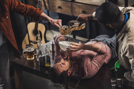 朋友们在漏斗里倒啤酒和男人坐在桌上图片