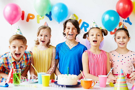 5个快乐的小孩在生日餐桌上摆着蛋糕背景图片
