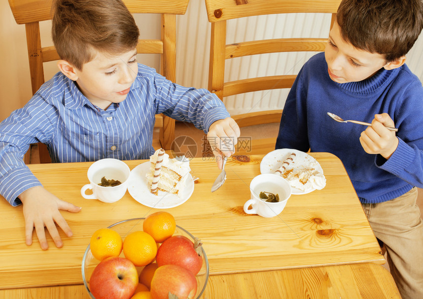 小可爱男孩们在木制吃甜点在家里室内图片