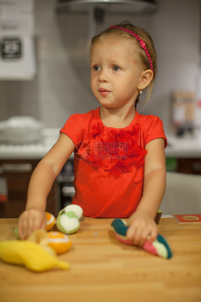 在厨房里玩水果和蔬菜的小可爱女孩图片