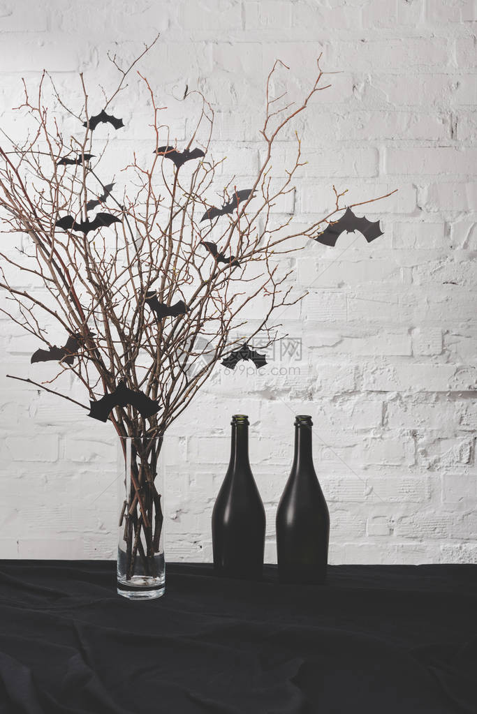 花瓶里有蝙蝠的干树枝和桌子上黑瓶子图片