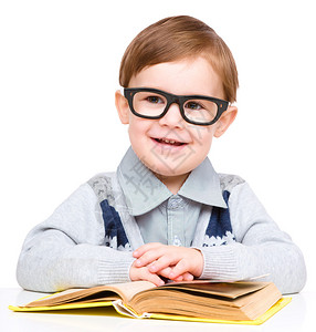 可爱的小孩玩书本和戴眼镜坐在桌子上图片