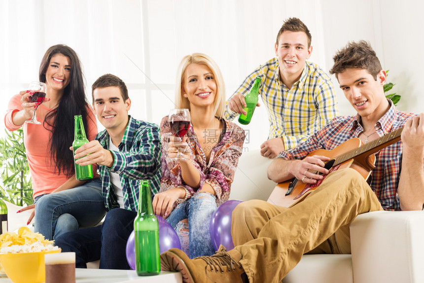 在家聚会上愉快的朋友们用瓶子和杯子敬酒图片