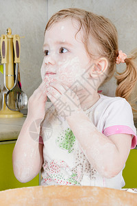 小女孩为面团筛面粉图片
