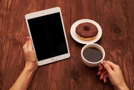 女手握平板电脑和咖啡杯的棕色木本底妇图片