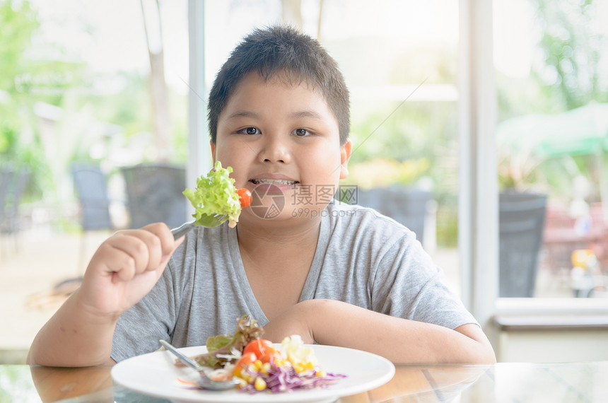 肥胖子享受吃可食用的沙拉饮食和图片