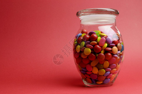 GlassJar满是明亮多彩的宝盒和糖果封盖着红色橙背景上图片
