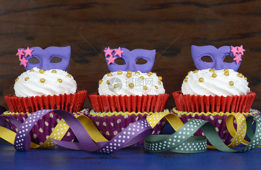 狂欢节蛋糕紫色面罩的杯子在生锈风格的深蓝图片