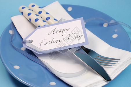 喜悦父亲日餐桌位设置紧贴的蓝色波尔卡圆点板和餐具与礼物图片