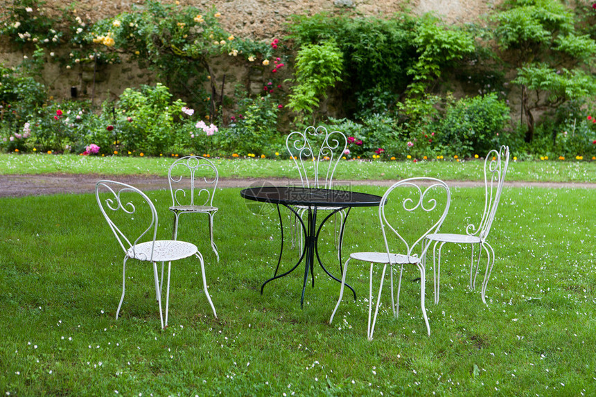 花园里的空桌子和四把白色椅子图片