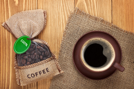 咖啡杯和小袋子用木桌上的豆子从上面看图片