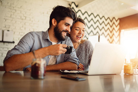 快乐的情侣在咖啡馆的笔记本上冲浪夫妻在线购图片