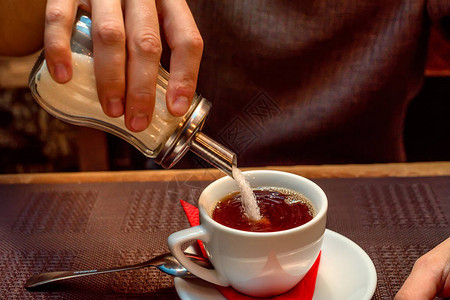 糖消费概念手在杯茶中加入白糖图片