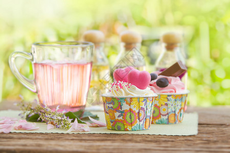 玫瑰茶和甜美的蛋糕在花园的桌子上图片