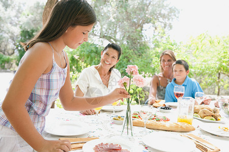快乐的家庭坐在户外的餐桌旁一起吃饭图片