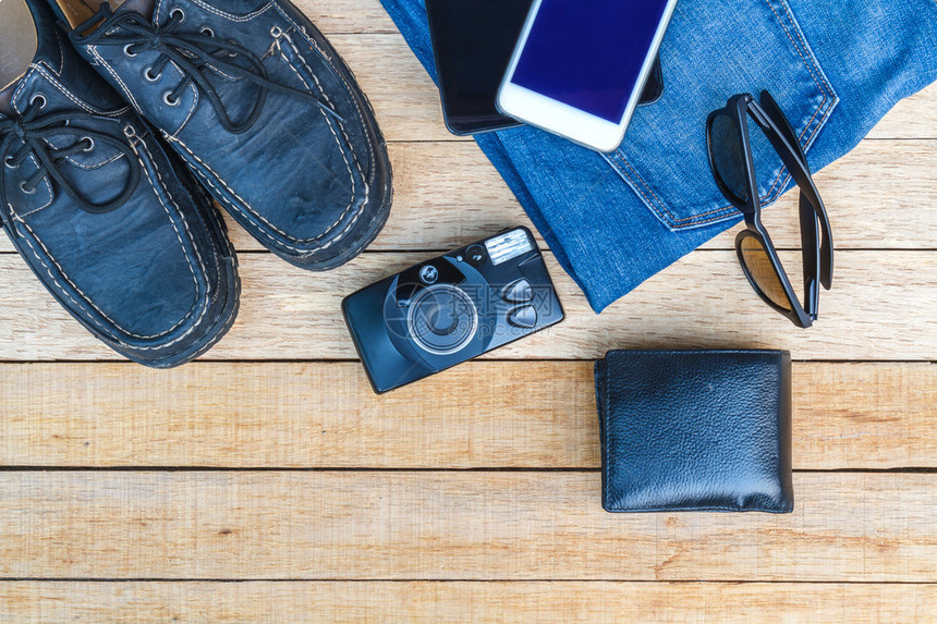 随身携带照相机智能手机平板电脑鞋子太阳镜钱包和木制桌子上的图片