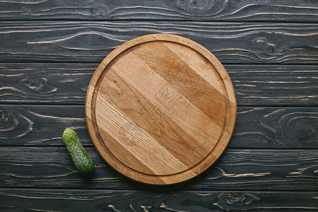 深色木桌上的切菜板和黄瓜图片