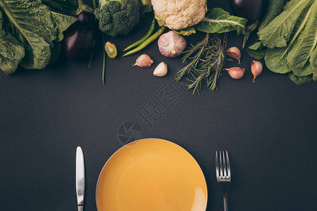 灰色表面有蔬菜的刀叉和盘子的顶部视图图片