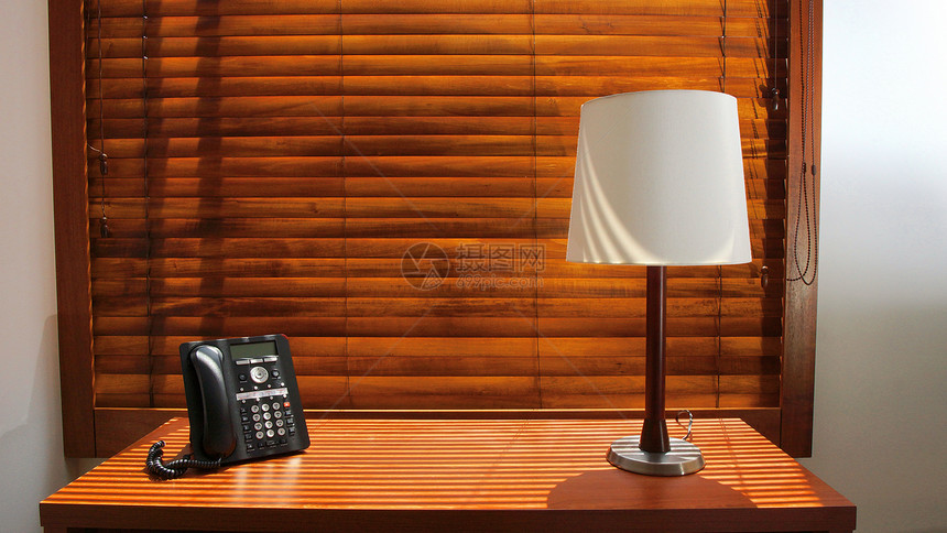 木制桌有灯和电话在旅馆房间背景图片