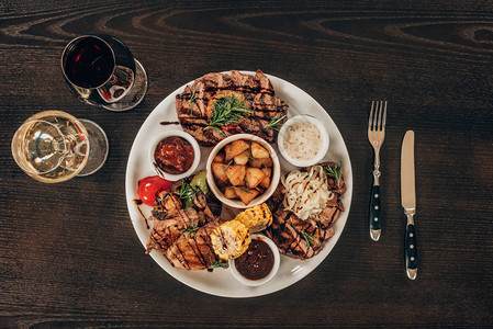 木桌上的牛排鸡翅和葡萄酒的盘子的顶部视图图片
