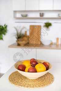 厨房餐桌上碗中橙子和李子的近景图片