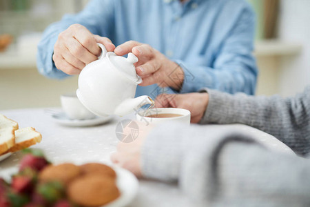 高官用白瓷茶壶的手把茶倒在图片