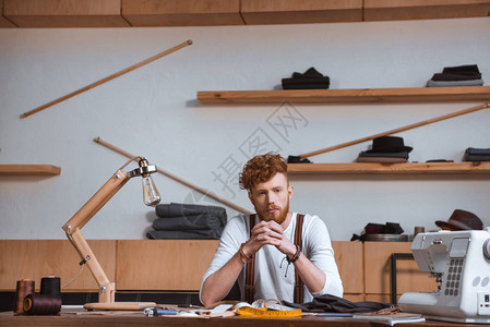 时尚的年轻男时装设计师坐在工作图片