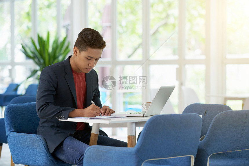 集中精神的亚洲男子坐在办公室大厅图片