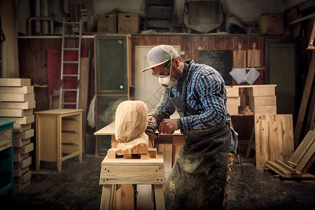 身着工作服的建造者锯从木头上切下雕塑图片