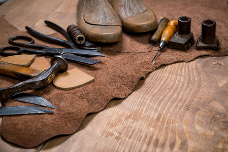 木制背景上的皮革工艺具集鞋匠的工作场所一块隐藏和工作桌背景图片