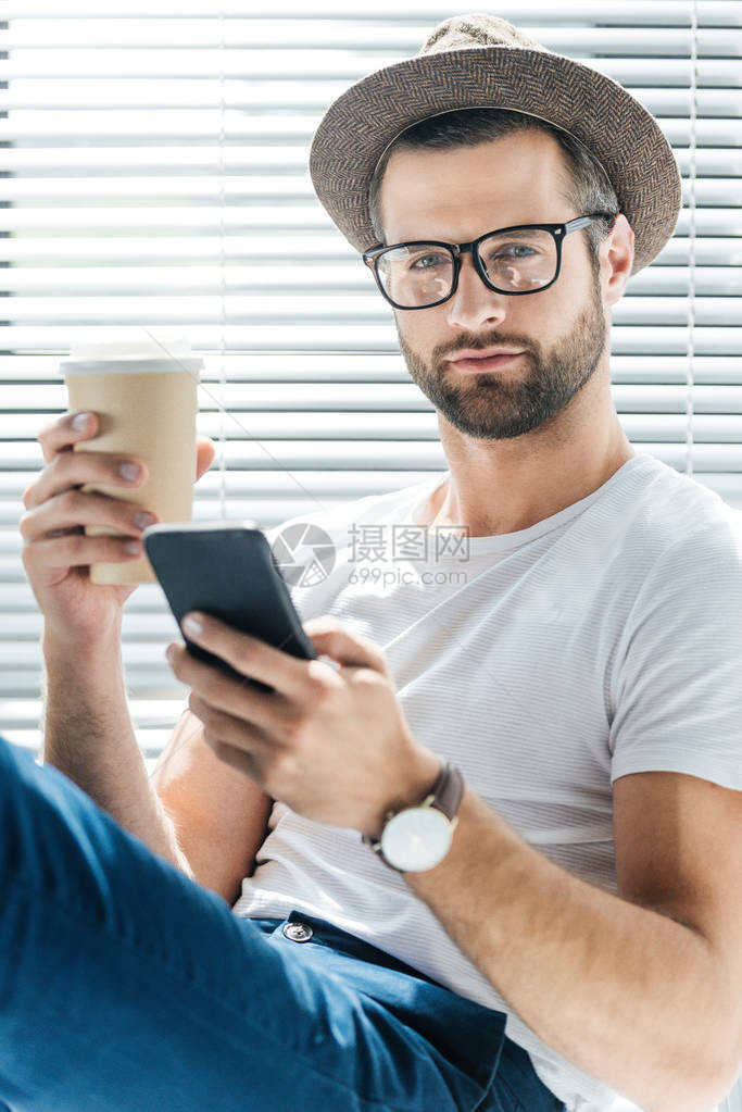 戴眼镜和帽子的帅男人拿着咖啡图片