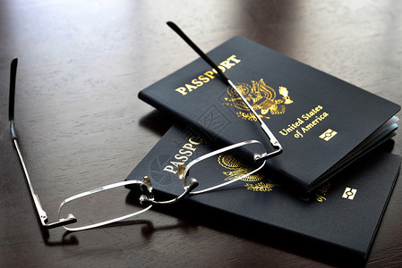 木桌上的美国护照和眼镜高清图片