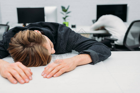 年轻经理在现代办公室工作时睡过头的过度图片