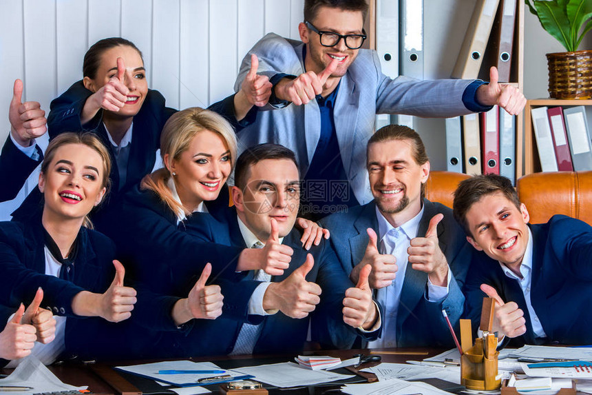 商业人员办公室的团队生活对坐在桌子上玩大拇指很满意在幕后有图片