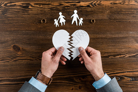 男人用家人和订婚戒指在木桌上握着撕裂的心脏图片