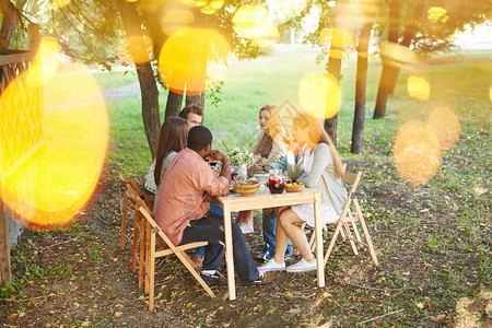 一群朋友坐在户外感恩节餐桌旁图片