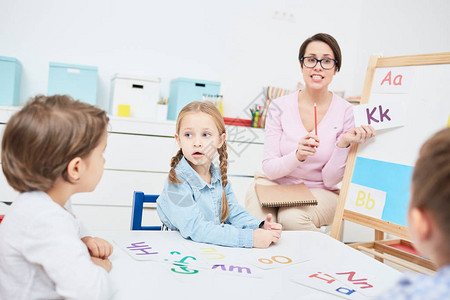 年轻教师在学习字母表时向幼儿园童发函图片