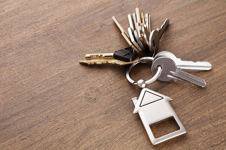 一堆钥匙在木桌背景的房子形钥匙扣上房地产概念或带复印空图片