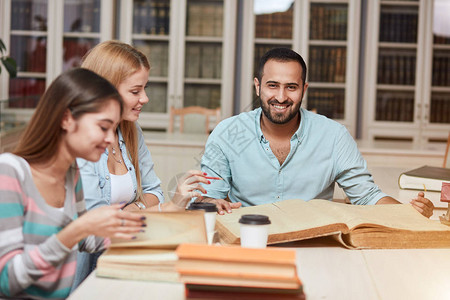 快乐的年轻大学生在图书馆书籍大学图书馆里的一图片